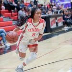 A girl dribbles the basketball on a court.