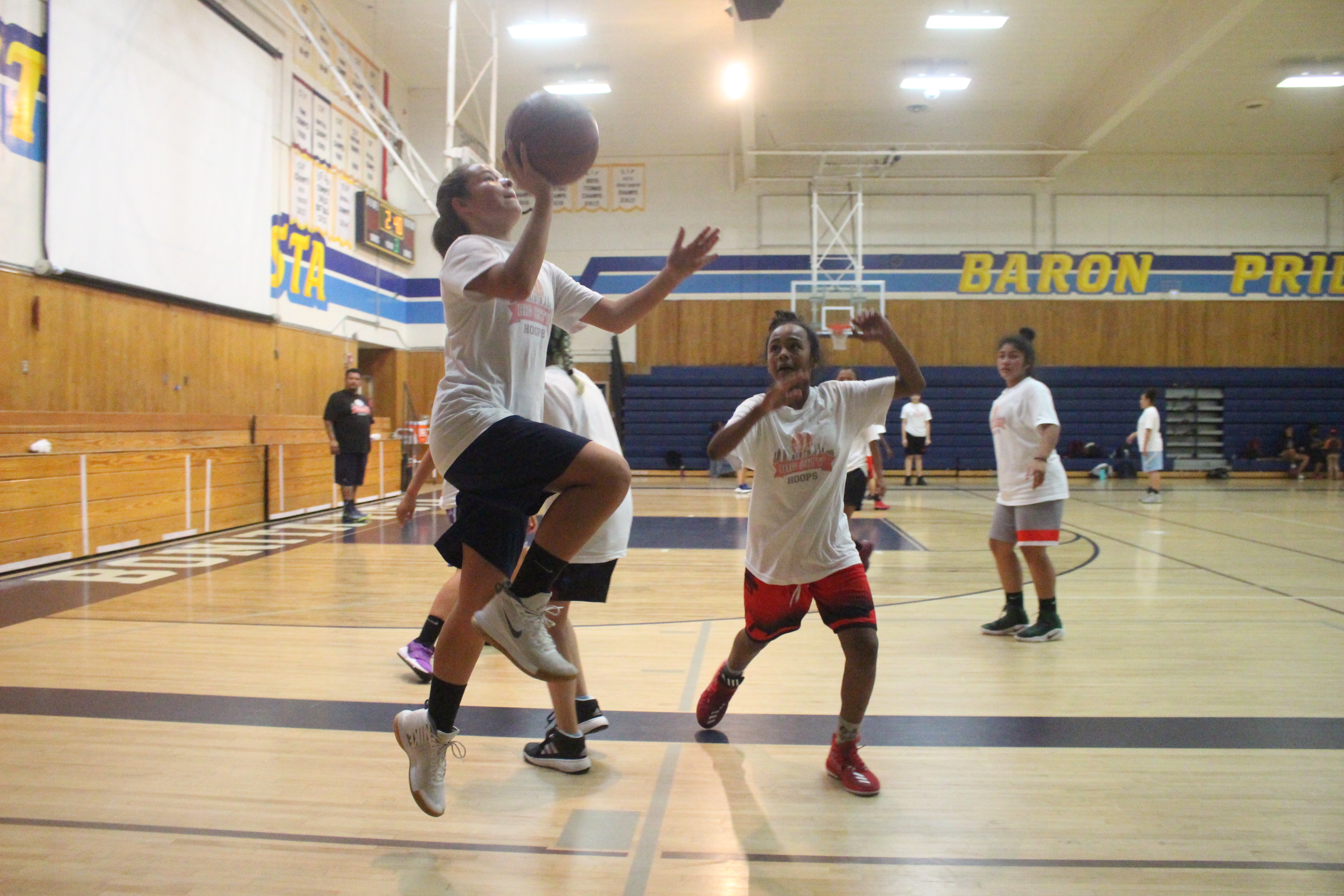 A group of people playing basketball in the gym.