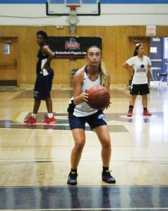 A girl holding onto a basketball in the gym